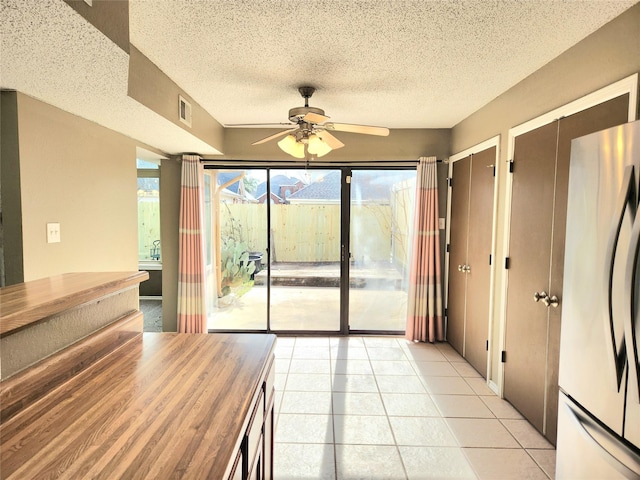 interior space featuring light tile patterned flooring, ceiling fan, and a textured ceiling