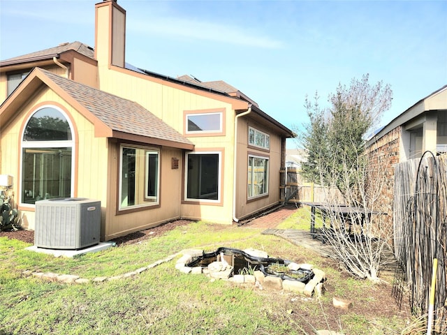 back of house featuring central AC unit and a lawn