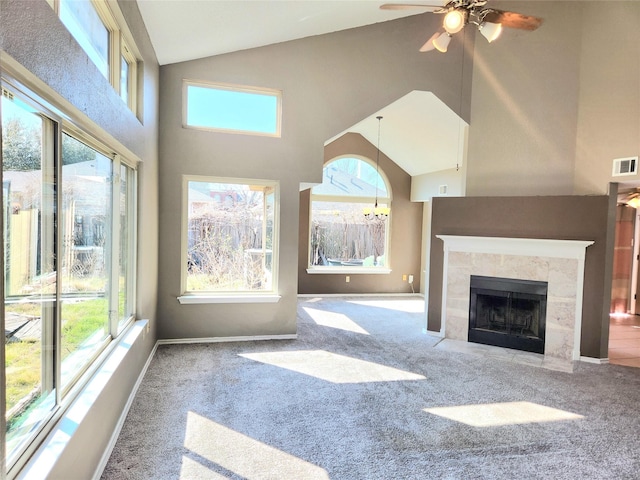 unfurnished living room featuring high vaulted ceiling, a tiled fireplace, carpet floors, and a wealth of natural light