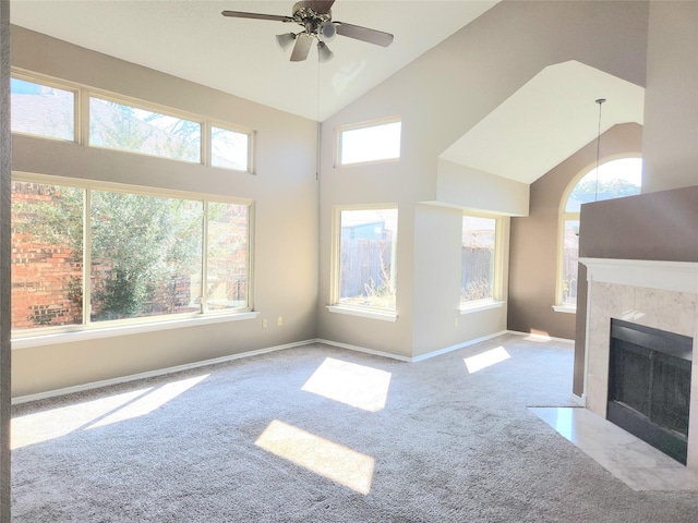 unfurnished living room featuring light colored carpet, a healthy amount of sunlight, high vaulted ceiling, and a tile fireplace