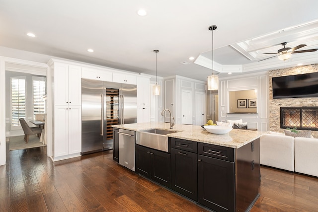 kitchen with dark hardwood / wood-style floors, decorative light fixtures, an island with sink, sink, and stainless steel appliances