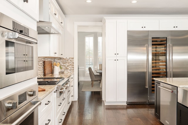 kitchen featuring stainless steel appliances, light stone countertops, dark hardwood / wood-style floors, and white cabinets