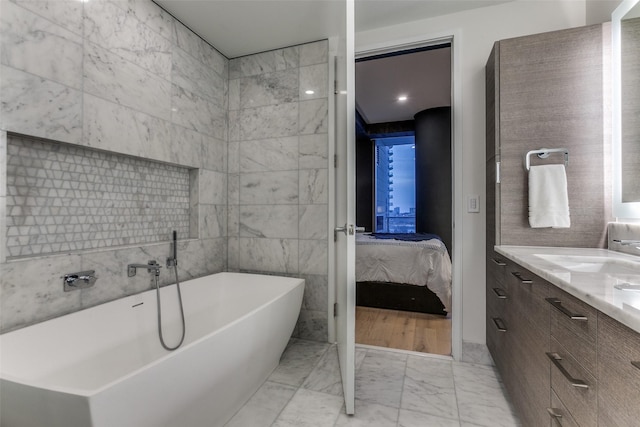 bathroom with a bathing tub, tile walls, and vanity