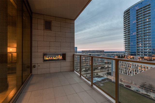 balcony at dusk featuring a fireplace