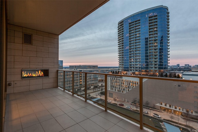 balcony at dusk featuring a fireplace