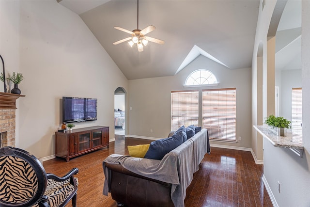 living room with ceiling fan, high vaulted ceiling, dark wood-type flooring, and a fireplace