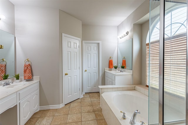 bathroom with vanity, tile patterned flooring, and a relaxing tiled tub