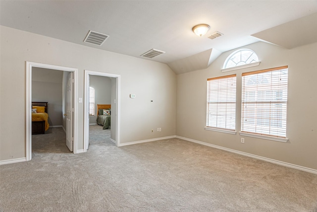 carpeted spare room with lofted ceiling