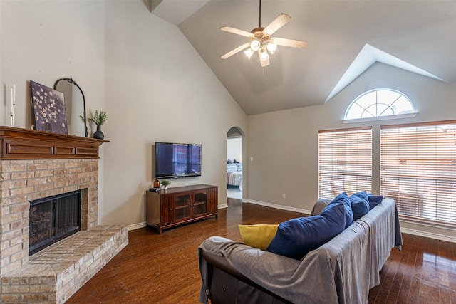 living room with dark hardwood / wood-style flooring, a brick fireplace, high vaulted ceiling, and ceiling fan