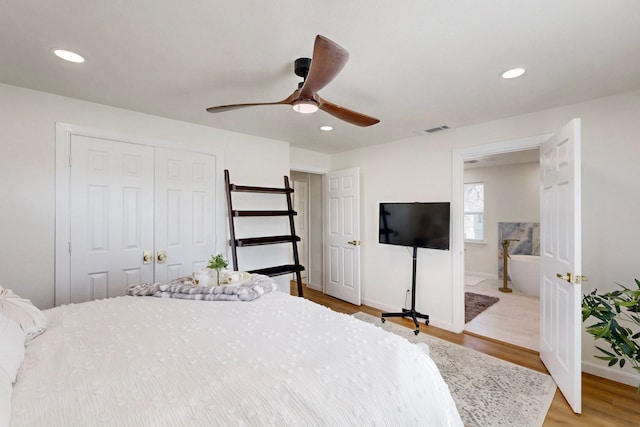 bedroom with connected bathroom, hardwood / wood-style floors, a closet, and ceiling fan