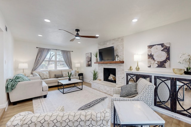 living room with ceiling fan, a fireplace, and light hardwood / wood-style flooring