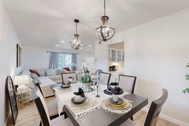 dining space with light hardwood / wood-style floors and a chandelier