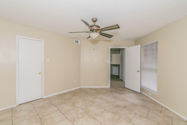 tiled empty room featuring ceiling fan and a textured ceiling