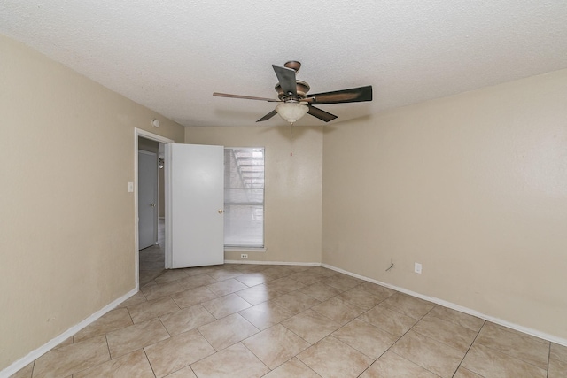 unfurnished room with ceiling fan, light tile patterned floors, and a textured ceiling