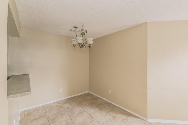 unfurnished room featuring an inviting chandelier, light tile patterned floors, and a textured ceiling