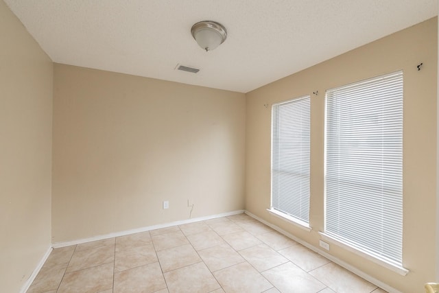 tiled empty room with a textured ceiling and a healthy amount of sunlight