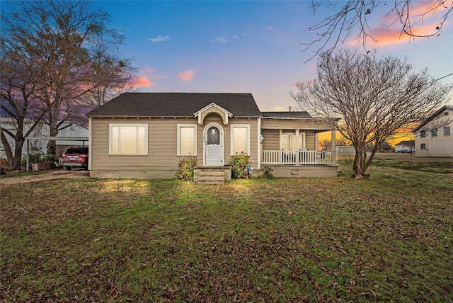 ranch-style home featuring a porch, a carport, and a lawn