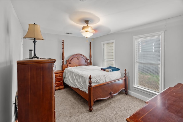 bedroom featuring multiple windows, light carpet, and ceiling fan