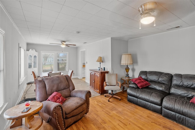 living room featuring ceiling fan, ornamental molding, and light wood-type flooring