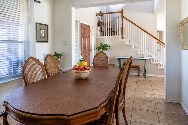 tiled dining space featuring baseboards and stairway