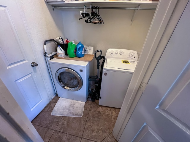 clothes washing area with laundry area, dark tile patterned flooring, and washer and dryer