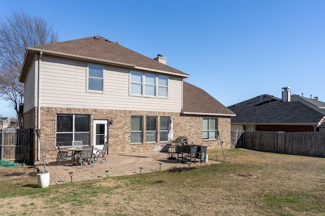 rear view of property with fence, a lawn, and brick siding