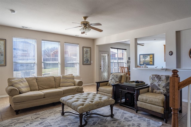 tiled living area with baseboards, visible vents, and a ceiling fan