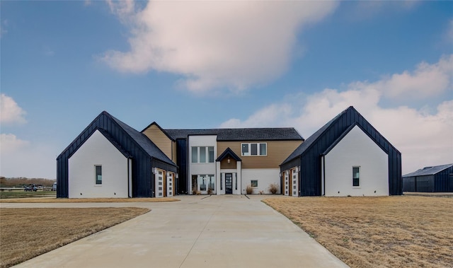 modern farmhouse featuring a front lawn, board and batten siding, and concrete driveway