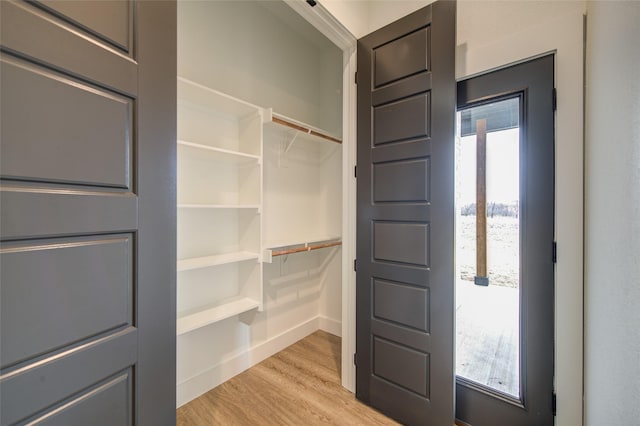 walk in closet with light wood-style floors