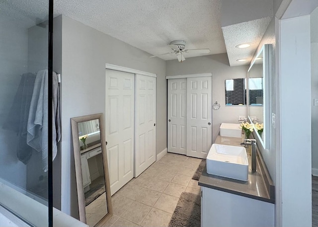 bathroom with double vanity, a closet, a ceiling fan, tile patterned flooring, and a sink