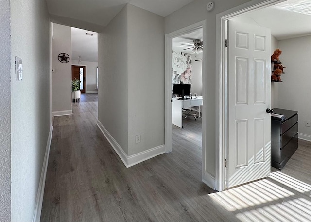 hallway featuring dark wood finished floors and baseboards