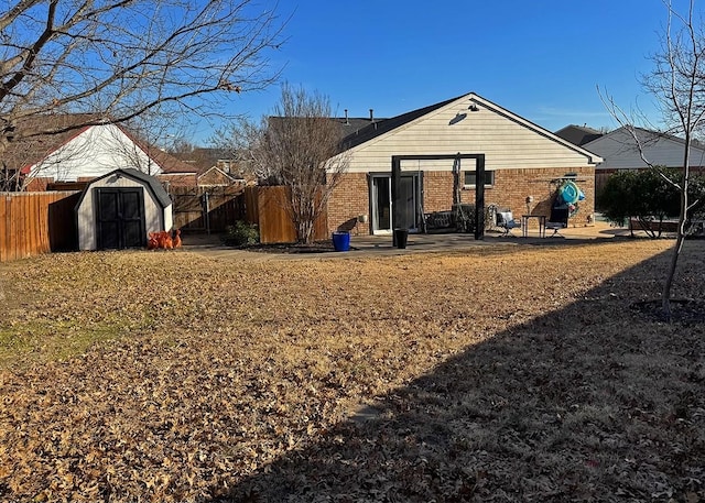 back of house with brick siding, fence, and a shed