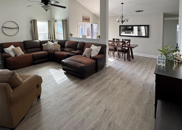 living area featuring light wood finished floors, baseboards, visible vents, high vaulted ceiling, and ceiling fan with notable chandelier