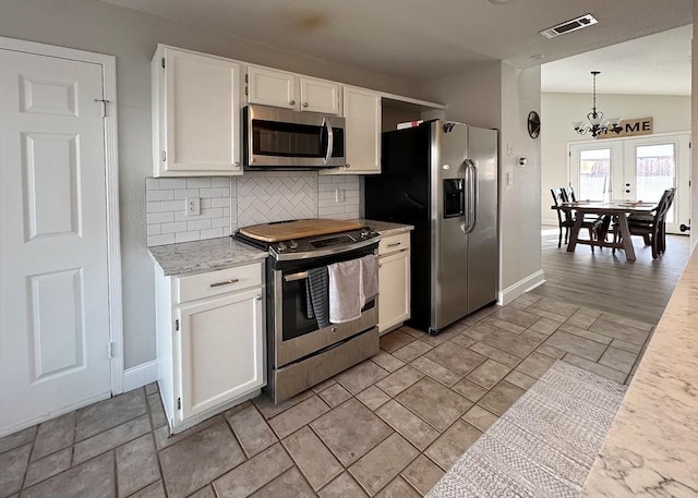 kitchen with stainless steel appliances, white cabinetry, vaulted ceiling, backsplash, and decorative light fixtures