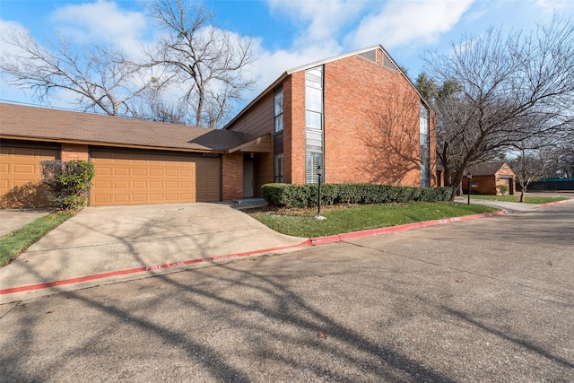 view of front of home with driveway, an attached garage, and brick siding