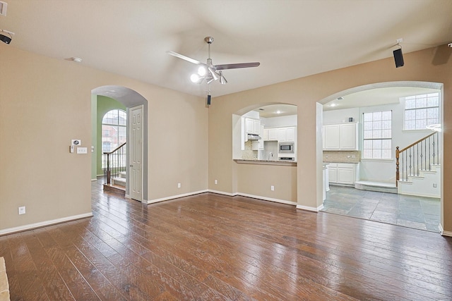 unfurnished living room featuring dark hardwood / wood-style flooring, a wealth of natural light, and ceiling fan