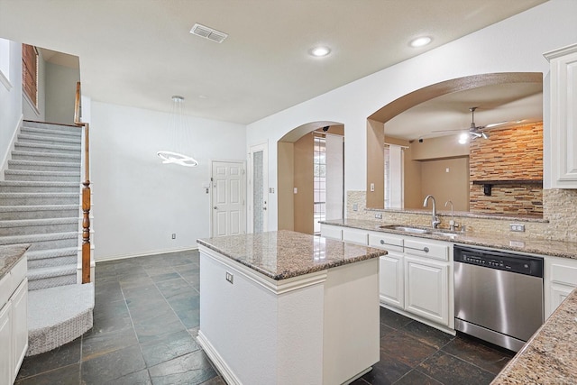 kitchen with sink, white cabinetry, light stone counters, dishwasher, and a kitchen island