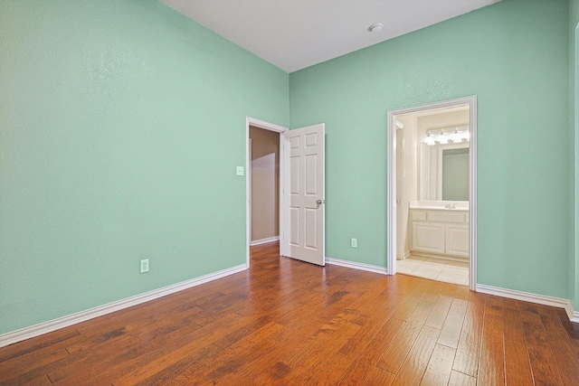 unfurnished bedroom featuring wood-type flooring and ensuite bath