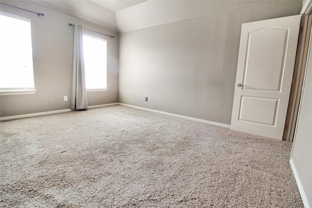 carpeted spare room featuring lofted ceiling