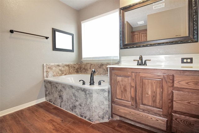 bathroom with hardwood / wood-style flooring, vanity, and tiled tub