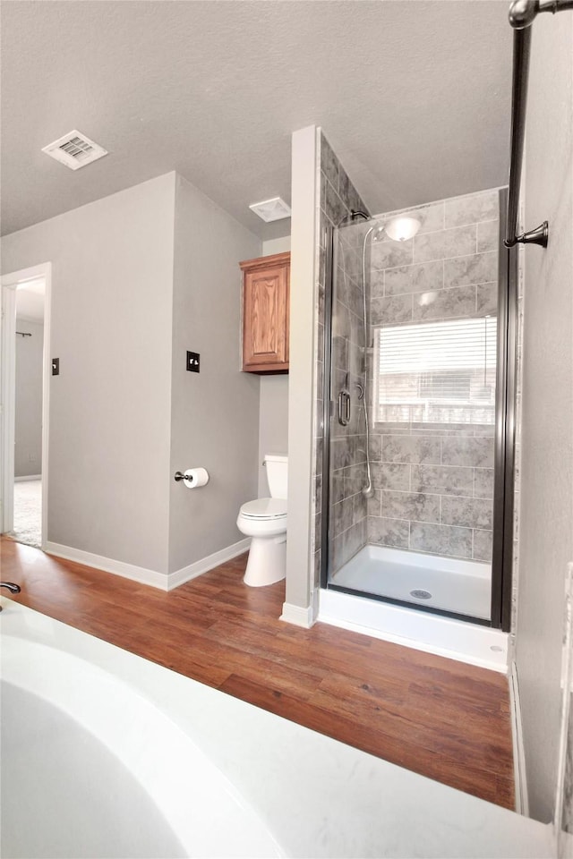 bathroom with walk in shower, toilet, and hardwood / wood-style floors