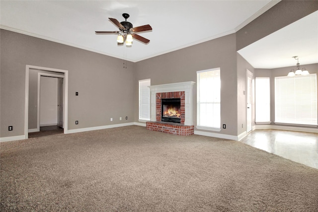 unfurnished living room featuring ceiling fan with notable chandelier, a fireplace, ornamental molding, and carpet