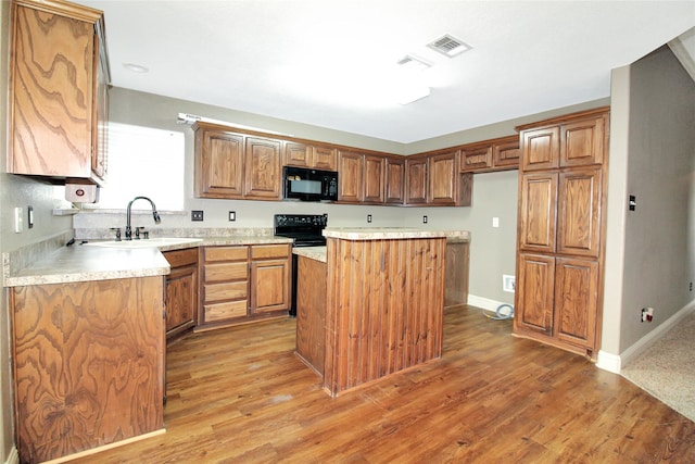 kitchen featuring wood-type flooring, a center island, sink, and black appliances