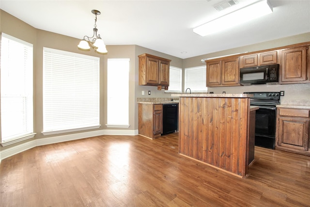 kitchen with pendant lighting, dark hardwood / wood-style floors, black appliances, a kitchen island, and a chandelier