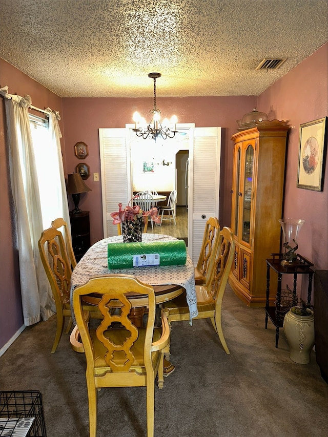 dining area featuring an inviting chandelier, dark carpet, and a textured ceiling