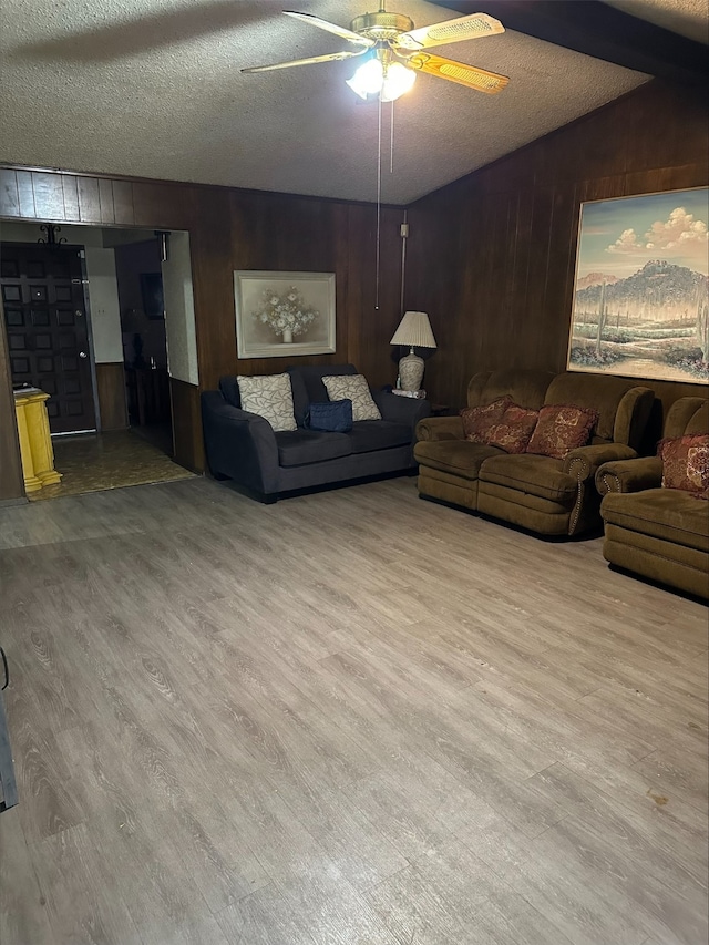 living room with lofted ceiling, wood walls, a textured ceiling, ceiling fan, and hardwood / wood-style floors