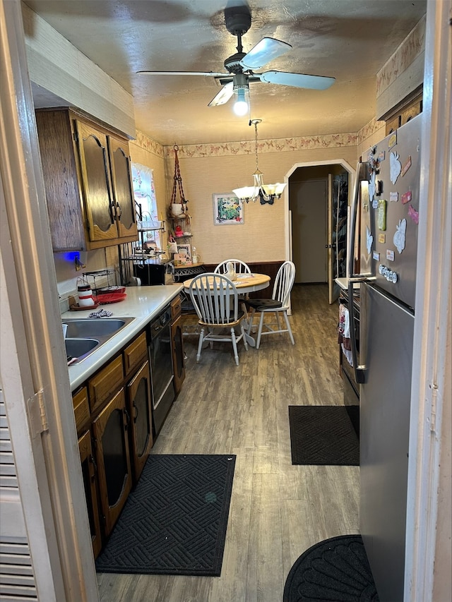 kitchen with sink, light hardwood / wood-style flooring, stainless steel fridge, ceiling fan with notable chandelier, and decorative light fixtures