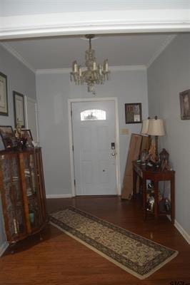 foyer entrance with hardwood / wood-style floors, crown molding, and a notable chandelier