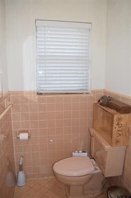 bathroom featuring toilet, tile patterned flooring, and tile walls