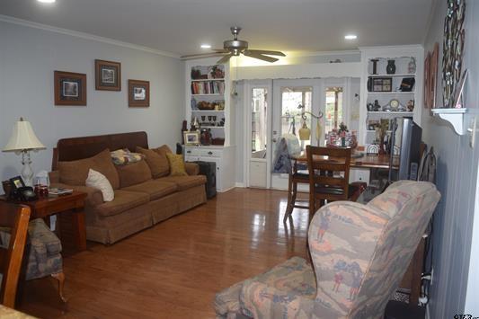 living room featuring hardwood / wood-style flooring, ceiling fan, crown molding, and french doors